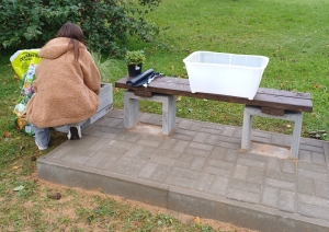 Cilvēks kopj augus pie soliņa
