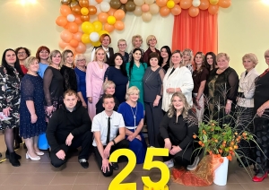 Cilvēki pozē pie svētku dekorācijām ar skaitli „25”
