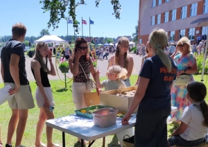 Apmeklētāji piedalās aktivitātēs saulainā brīvdabas pasākumā