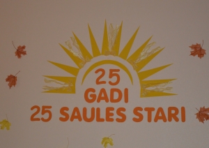 ienas noformējums ar uzrakstu „25 gadi. 25 Saules stari.”