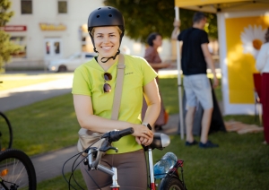 Sieviete velosipēda ķiverē stāv pie velosipēda