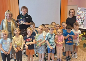Bērnu grupa ar skolotājām un grāmatām