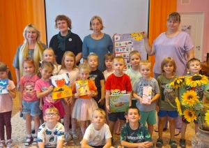 Bērnu grupa ar skolotājām un grāmatām
