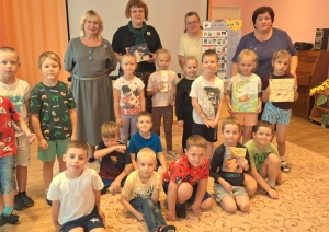 Bērnu grupa ar skolotājām un grāmatām