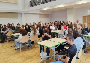 Jaunieši sēž grupās pie galdiem un piedalās pasākuma aktivitātēs