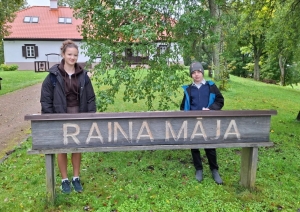 Divi skolēni pie „Raiņa mājas” zīmes