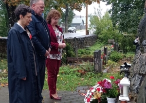 Trīs cilvēki piemin aizgājušos pie piemiņas vietas ar ziediem
