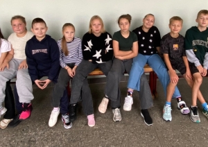 Skolēnu grupa sēž rindā uz sola