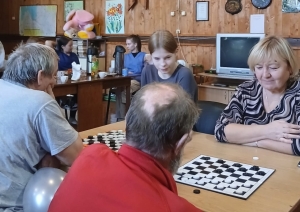 Cilvēki spēlē dambreti pie galda