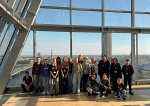 Skolēnu grupa uz Rīgas panorāmas fona