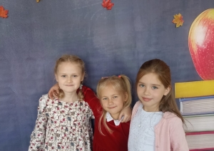 Trīs meitenes pozē pie rudens tematikas fona