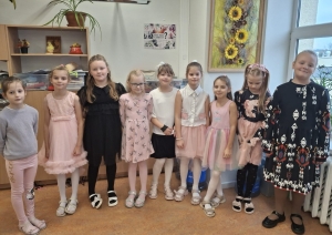 Skolnieces svinīgi pozē klases telpā