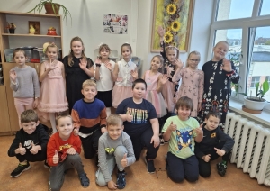 Skolēnu grupa kopā pozē un māj ar rokām