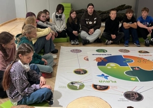 Skolēni muzejā iepazīst dabas materiālus un pēta attēlu ar ekosistēmas barības ķēdēm