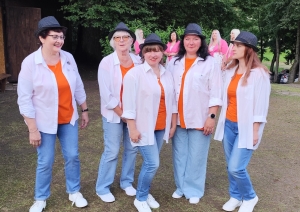 Sieviešu radošais kolektīvs baltos kreklos un oranžos t-kreklos