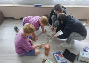 Bērni un jaunietes uz grīdas kopā spēlē domino