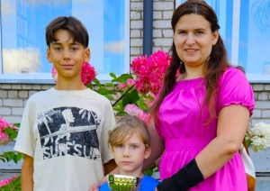 Mamma ar diviem bērniem pie ziediem