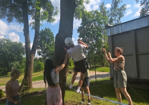 Jaunietis drošināšanas ekipējumā kāpj uz horizontālas troses