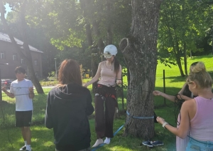 Dalībniece drošināšanas ekipējumā balansē uz troses