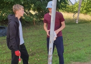 Divi jaunieši nostiprina volejbola tīkla stabu