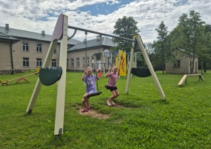 Bērni šūpojas rotaļu laukuma šūpolēs