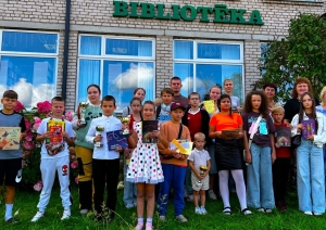 Bērni un pieaugušie pie bibliotēkas