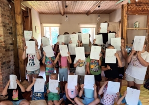 Bērni telpās rāda savus zīmējumus radošās nodarbības laikā