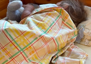Bērns diendusas laikā guļ bērnudārza gultiņā