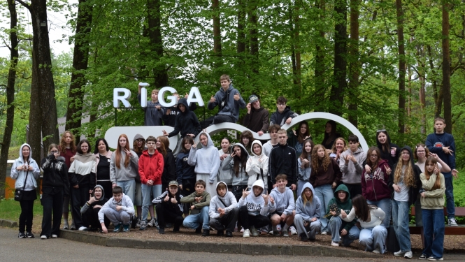 Skolēnu grupa pie Rīgas Zoodārza zīmes