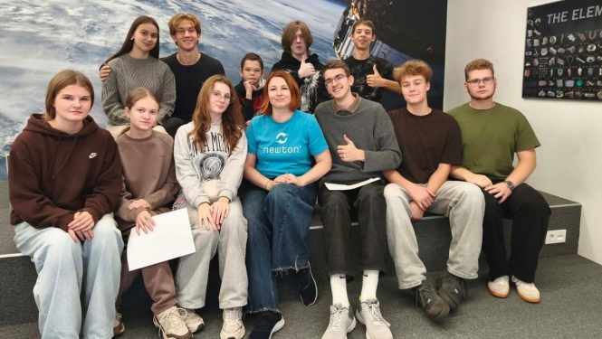Skolēnu grupa kopā skolotāju pie kosmosa attēla